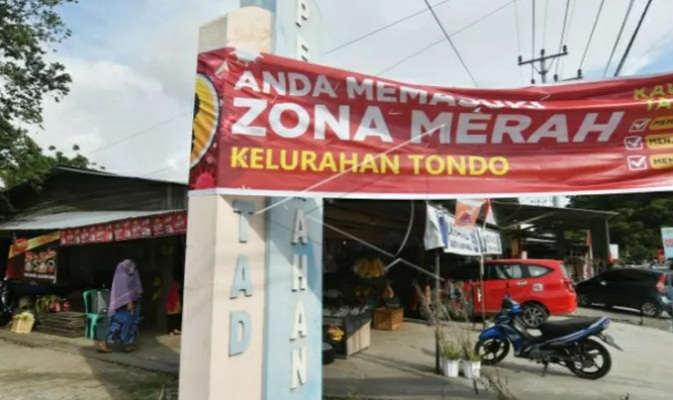 Sebuah baliho berisi peringatan wilayah zona merah COVID-19 terpasang di Kelurahan Tondo di Palu, Sulawesi Tengah,